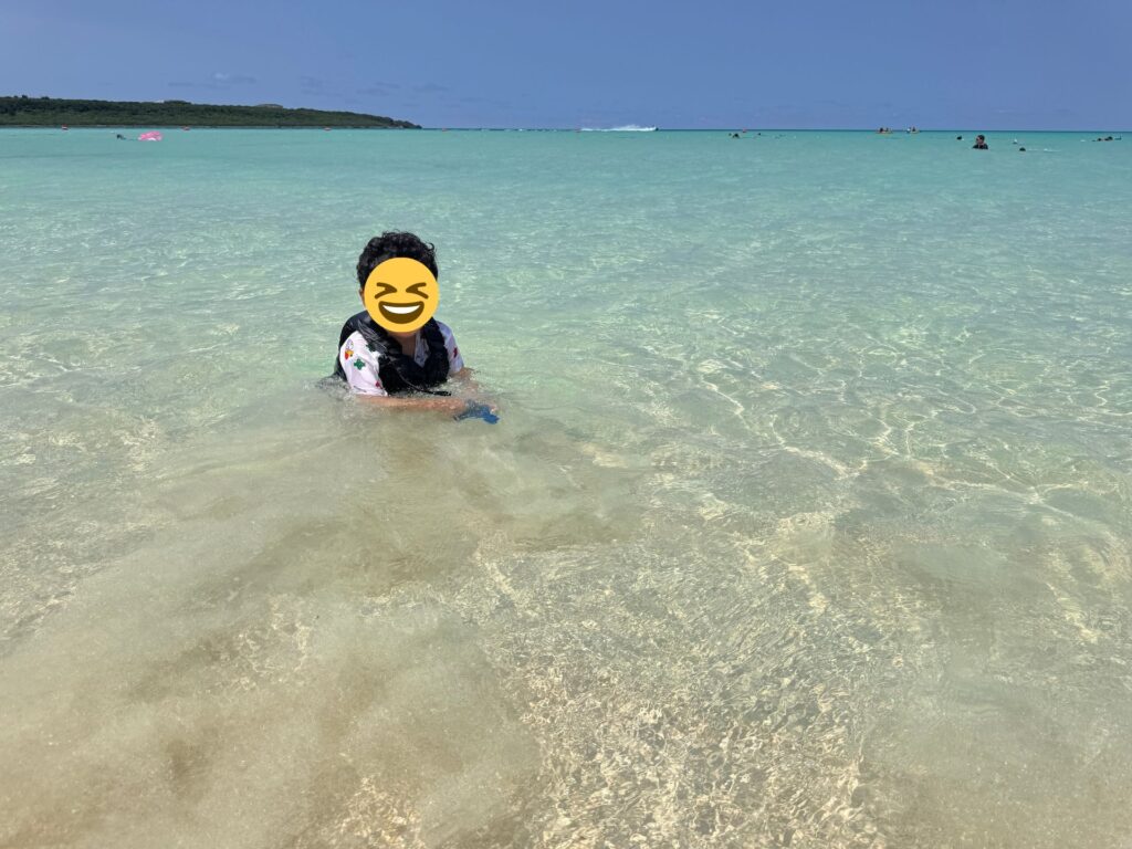 与那覇前浜ビーチで海遊びを楽しむ子供。透明度の高いエメラルドグリーンの海が広がる