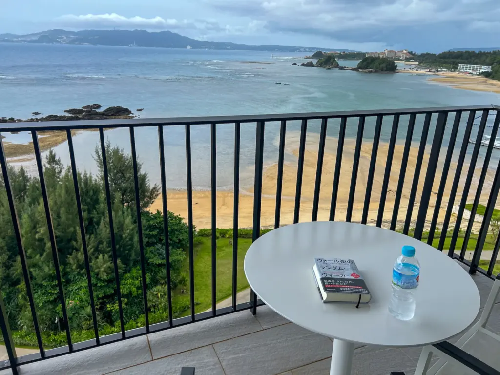 Balcony at Halekulani Okinawa with ocean view, book, and bottled water