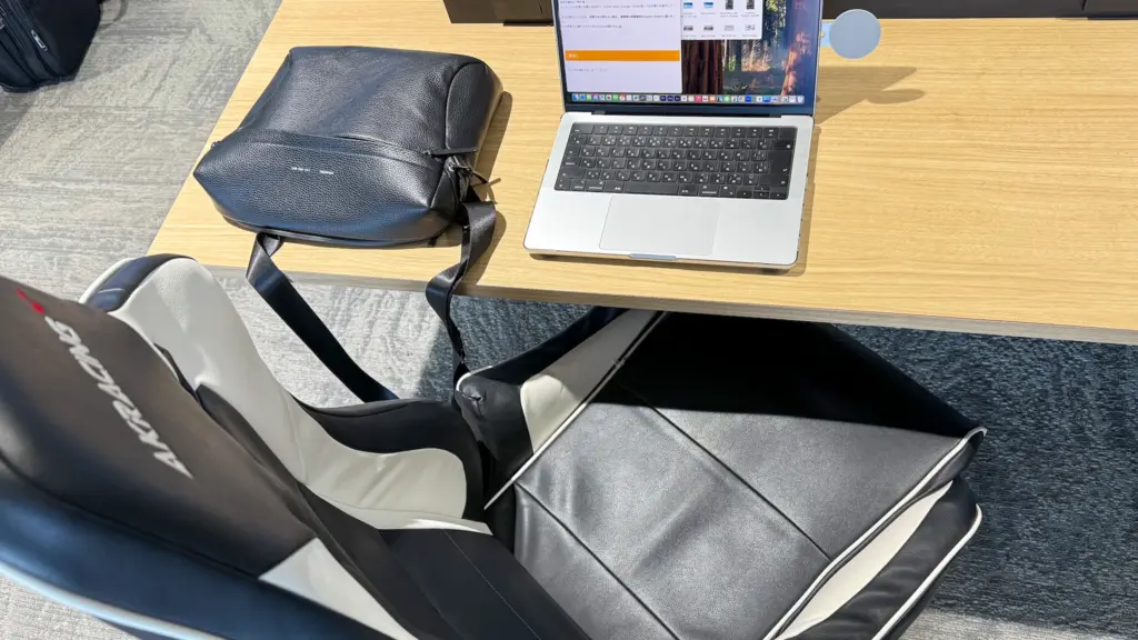 GRAMS28 171 Laptop Sling in use at an airport lounge, placed next to a MacBook Pro.