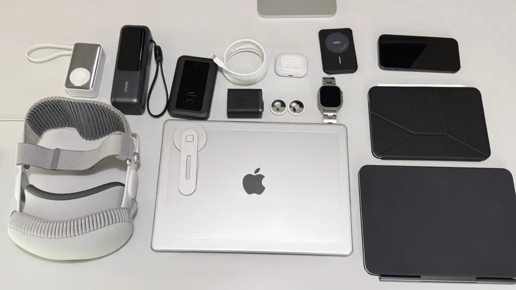 旅行バッグに入れるAppleガジェット一覧。MacBook Pro、iPad Pro 11、iPad mini、iPhone 16 Pro、Apple Watch Ultra 2、AirPods Pro 2、Vision Pro、モバイルバッテリー、WiFiルーターなどを並べた写真