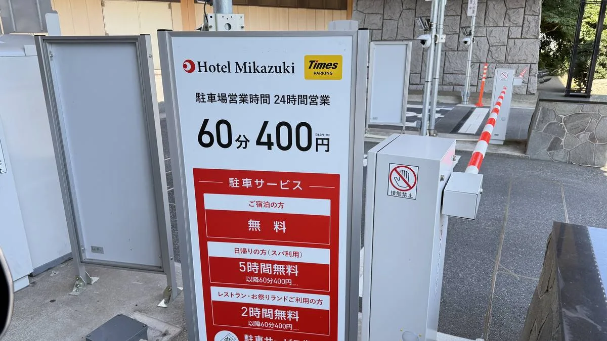 ホテル三日月 駐車場ゲートの料金看板。宿泊者は無料、日帰りスパ利用は5時間無料・以降60分400円